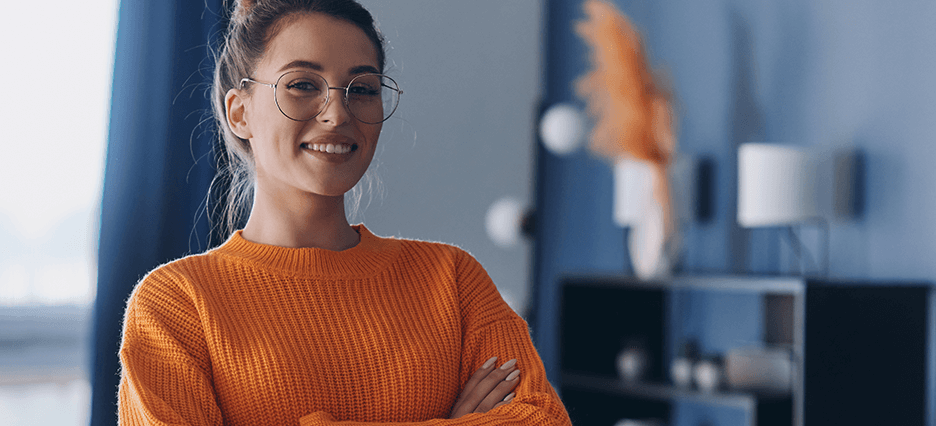 Attraktive junge Frau mit Brille und orangenem Pullover