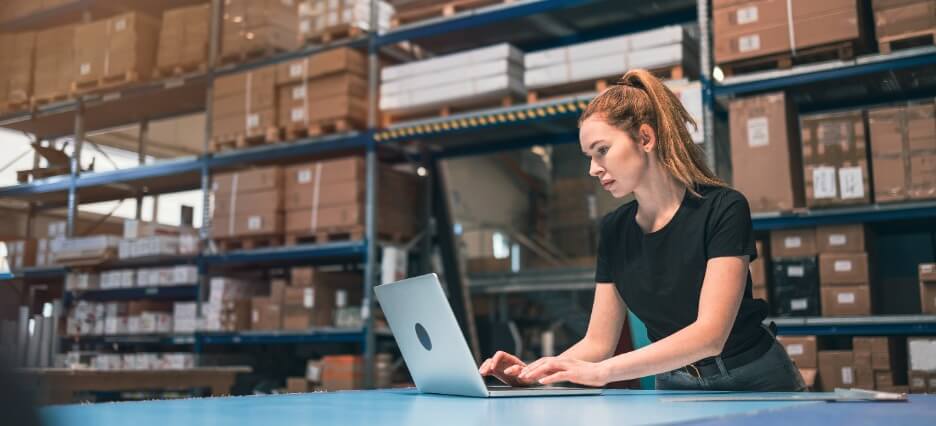 E-Commerce Manager arbeitet am Laptop im Warenlager