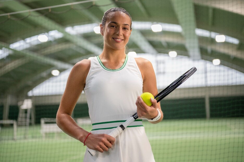 Weibliche Tennisspielerin steht in moderner Tennishalle