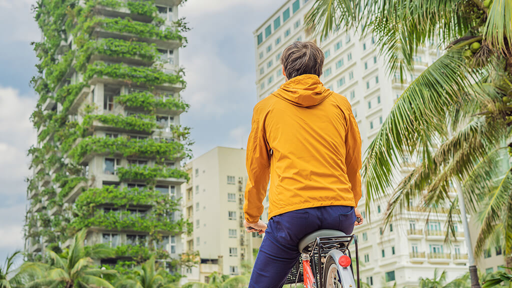 Mann auf Fahrrad blickt auf vertikalen Garten an einem Hochhaus